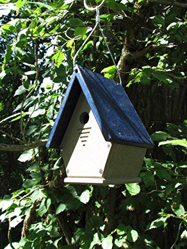 Unknown artist, handcrafted birdhouse hanging in a tree, featuring a dark blue roof, light beige body, and ventilation slits.
