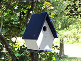 Recycled plastic birdhouse hanging from a tree in a garden featuring a navy blue roof white body and ventilation slots showcasing a charming rustic aesthetic
