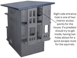 Product photo of the Nutty Mansion squirrel house showing multiple levels, a dark gray and navy blue color scheme, and two entry holes for predator escape.
