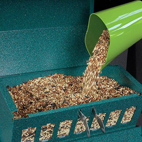 Close-up of filling the Absolute II Squirrel-Proof Bird Feeder with birdseed, showcasing the all-metal construction and green design.