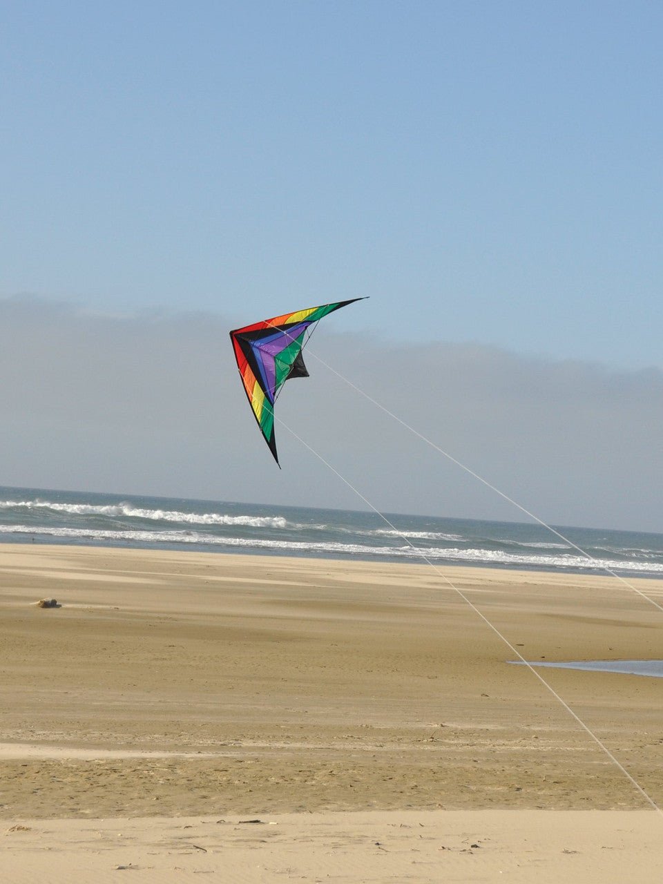 Rainbow Breeze 68" sport kite flying over a sandy beach with ocean waves in the background, perfect for beginners and entry-level stunt kite enthusiasts.