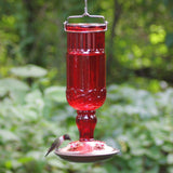 Perky-Pet 8119 Red Antique Glass Hummingbird Feeder with 24 oz capacity and decorative feeding ports in a garden setting
